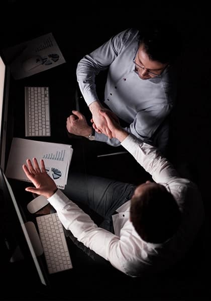 A man working on a laptop, and a woman reading papers